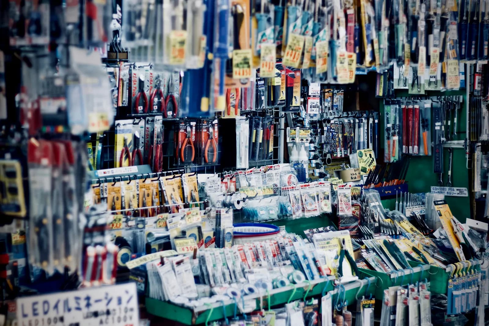 Un étal de quincaillerie bondé : pinces, fils à souder et outils à main sous emballage, accrochés et empilés