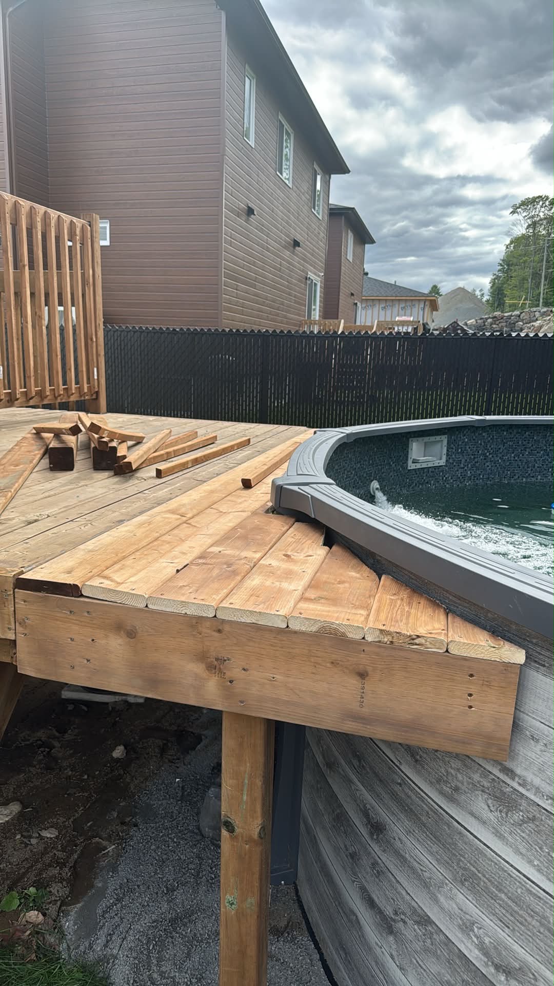 Le patio en bois traité de Simon en chantier, les planches 5/4x6 posées autour de la courbe de la piscine hors terre.