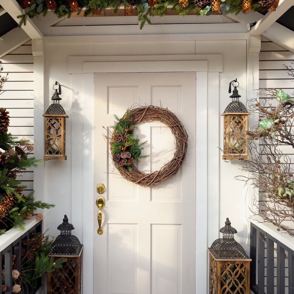 Porte d’entrée blanche abritée par un portique, décorée d’une couronne l’hiver