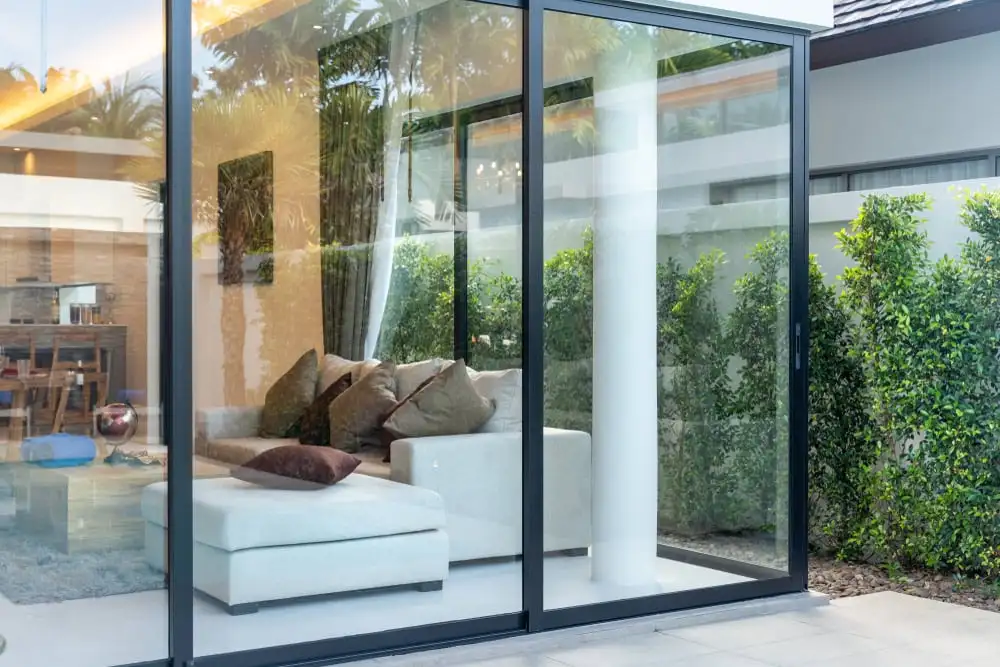 Porte patio coulissante à cadre d’aluminium noir donnant sur une cour aménagée